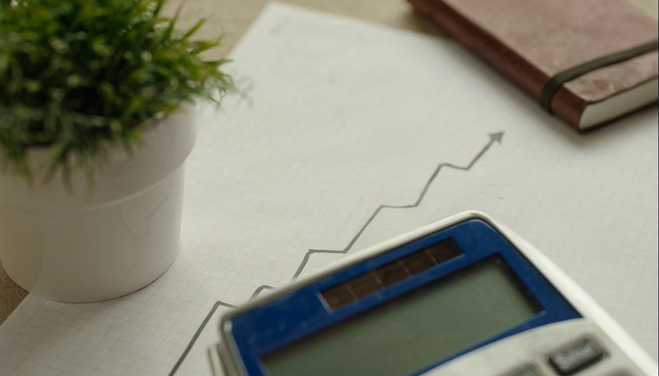 Small potted plant beside calculator and graph paper with ascending arrows