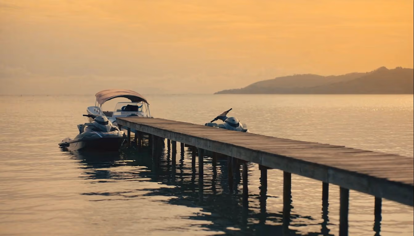Two jetskis and small speedboat moored at Indonesian wooden pier at golden hour